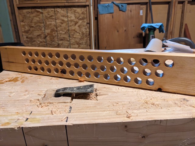 A lot of holes in a plank that will be the pinboard.