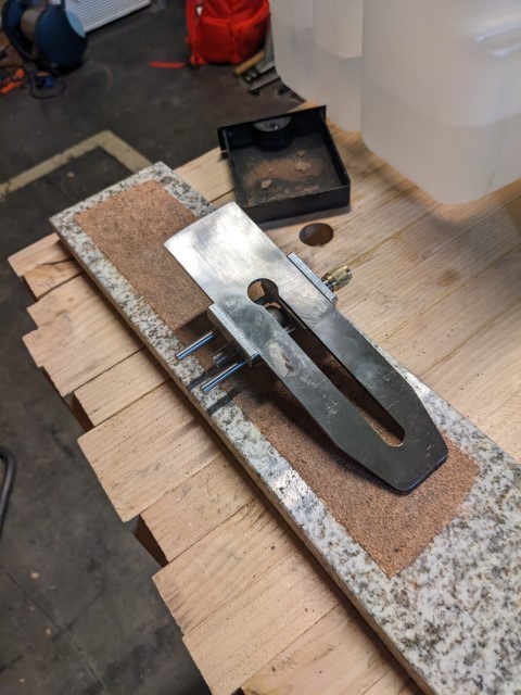 Hand-grinding a new bevel on a plane blade with coarse sandpaper on a flat granite slab.
